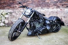 a black motorcycle parked next to a brick wall