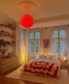 a bed room with a neatly made bed and a red light hanging from the ceiling