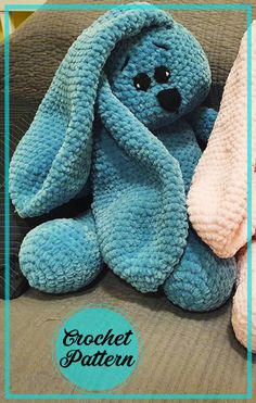 a blue stuffed animal sitting on top of a couch next to a pink teddy bear