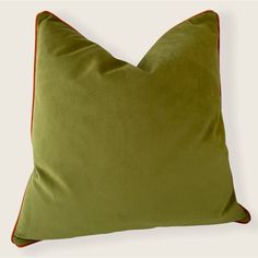 a green pillow with red piping on it