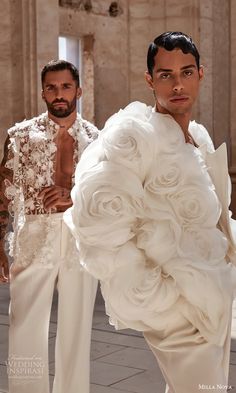 two men standing next to each other in white outfits