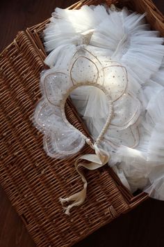 a wicker basket filled with white tutuffs and garters on top of a wooden table