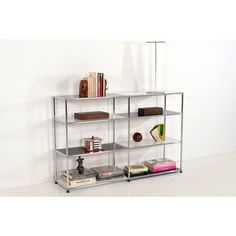 a metal shelf with books and other items on it in front of a white wall