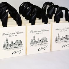 four bags with black ribbon tied to them on a white tablecloth and two are decorated with city skylines