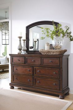 a dresser with a mirror and vases on top of it in a living room