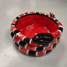 two red and black bowls sitting on top of a white table next to each other