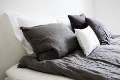 a bed topped with lots of pillows and blankets on top of it's headboard