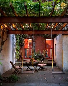 an outdoor dining area with hanging chairs and plants on the roof, surrounded by brick walls