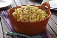 a red bowl filled with macaroni and cheese on top of a wooden table