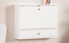 a white wall mounted cabinet with two drawers and a pen holder on the bottom shelf