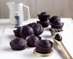 blueberry muffins on a white counter next to a spoon and cupcake tin