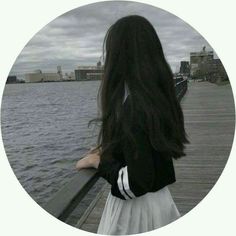 a girl standing on a pier looking at the water