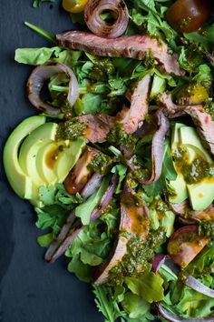 a salad with meat, avocado and onions on top is shown in this image