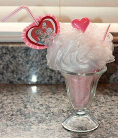 an ice cream sundae with heart shaped lollipops in a glass vase