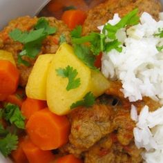 a white bowl filled with rice, meat and veggies next to carrots