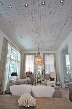 a living room filled with furniture and windows covered in wood plank ceilinging on top of a hard wood floor