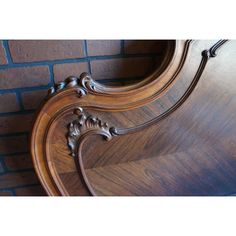 an ornate wooden bed frame against a brick wall