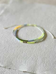 - Embrace the essence of spring with our delicately handcrafted double wrap bracelet. Meticulously made with a palette of soft pastel Miyuki beads, this piece captures the serene beauty of the season. Featuring light yellow, light orange, green, burgundy, baby blue, and clear beads, each colour is chosen to reflect the gentle hues of springtime. - The bracelet's adjustable design ensures a perfect fit for any wrist size, while the cream-coloured cord adds a touch of elegance and versatility. Des Bracelet Stands, Spring Colours, Soft Spring, Green Palette, Double Wrap Bracelet, Clear Beads, Boho Chic Jewelry, Miyuki Beads, Yellow Light