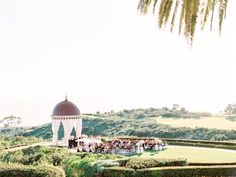 a group of people standing on top of a lush green field next to a white building