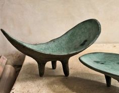 two green bowls sitting next to each other on top of a table in front of a white wall