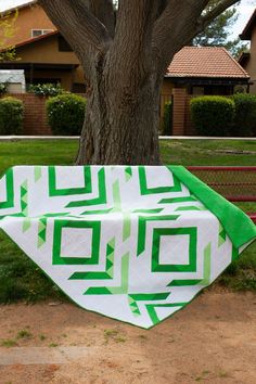 a green and white blanket sitting under a tree