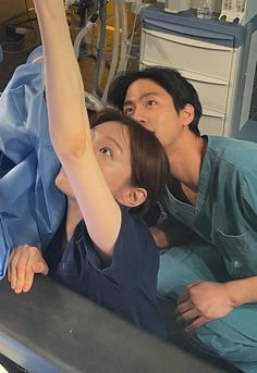 a man and woman in scrubs laying on a hospital bed