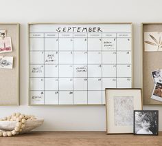 a wooden table topped with pictures and framed photos next to a calendar on a wall