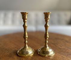 two golden candlesticks sitting on top of a wooden table