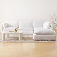 a white couch sitting on top of a hard wood floor next to a coffee table