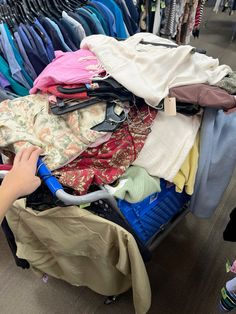 a person is reaching for clothes in a luggage cart on the floor at a clothing store