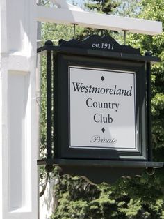 a sign for westmoreland country club hanging from the side of a white building