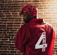 a man in a red jacket and hat standing next to a brick wall with the number 4 on it