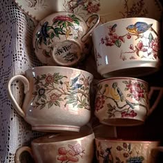 there are many cups and saucers on this tableclothed placemat, which is decorated with flowers and birds