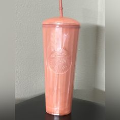 a pink starbucks cup sitting on top of a black table next to a white wall