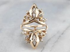 a gold ring with diamonds on it sitting on top of a marble surface, in front of a white background