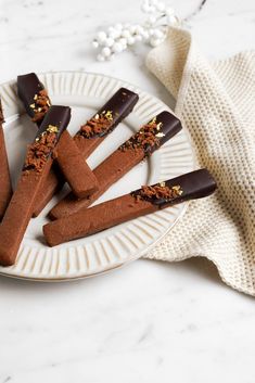 chocolate covered desserts are on a plate with sprinkles next to it