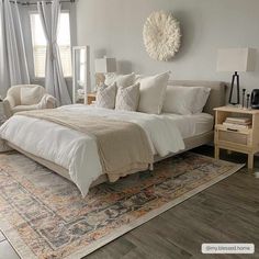 a large white bed sitting in a bedroom on top of a wooden floor next to a window