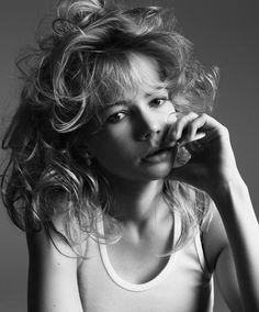 a black and white photo of a woman with her hair blowing in the wind, wearing a tank top