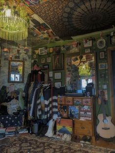 a room filled with lots of clutter and pictures hanging on the wall next to a guitar