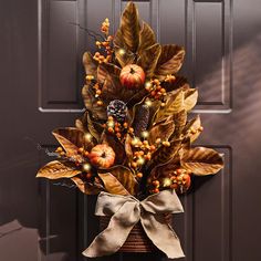 a door decorated with fall leaves, apples and acorns for the holiday season