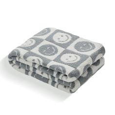 two gray and white blankets with smiley faces on them, one is folded over the other