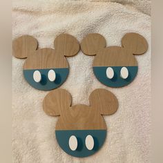 three wooden mickey mouse heads on a white towel with blue and brown circles around them