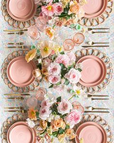 the table is set with pink plates and flowers