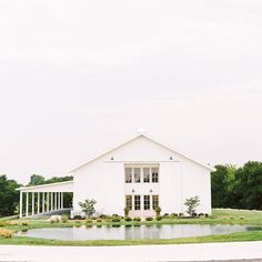 a large white building sitting on top of a lush green field next to a lake