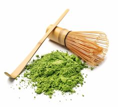 a whisk and green powder on a white background