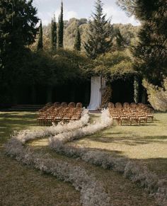 an outdoor ceremony setup with chairs and flowers on the grass, surrounded by trees in the background