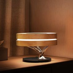 a modern table lamp sitting on top of a wooden shelf next to a curtained window