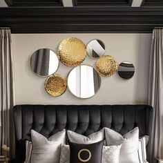 a black and gold bedroom with round mirrors on the wall above the bed, along with pillows