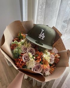 a baseball cap sitting on top of a bouquet of flowers in front of a window