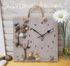 a clock made out of rocks and shells on a table next to a vase with flowers